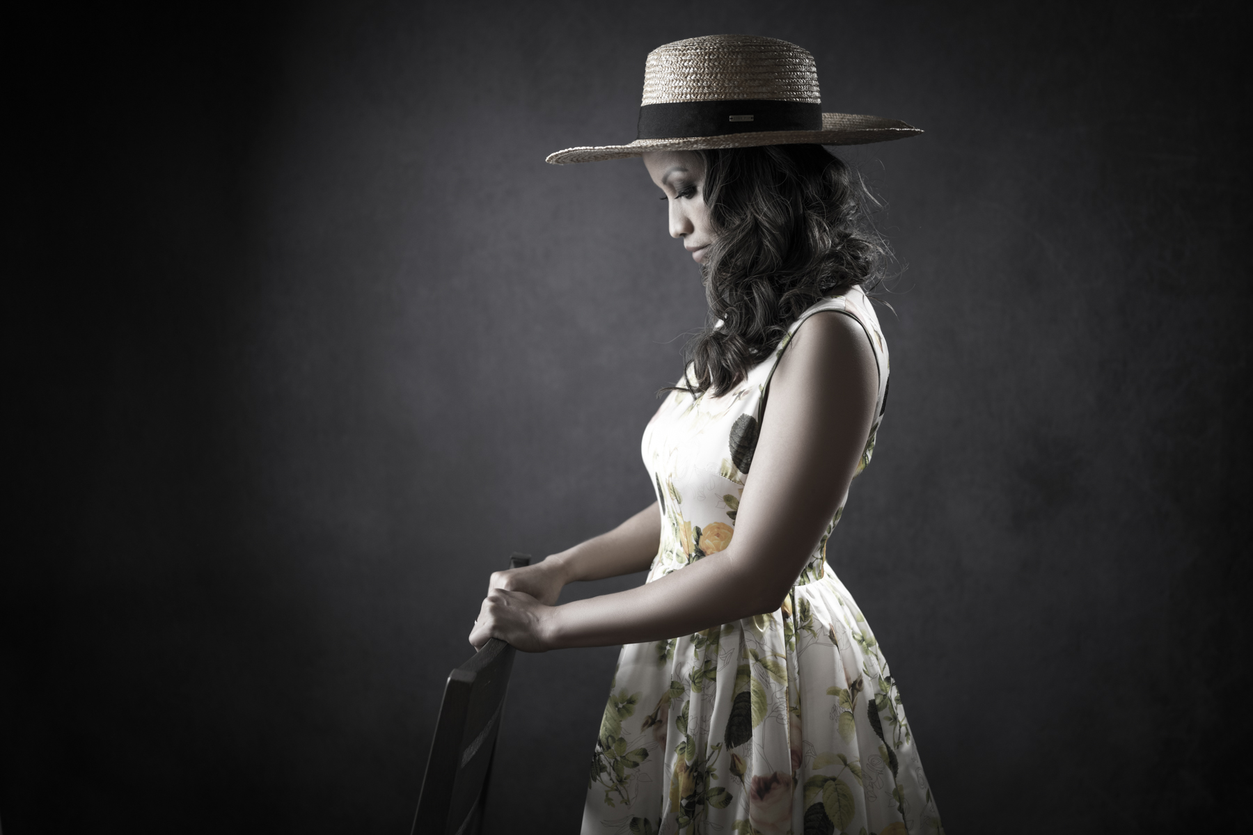 Profile portrait of a woman in a floral dress and straw hat