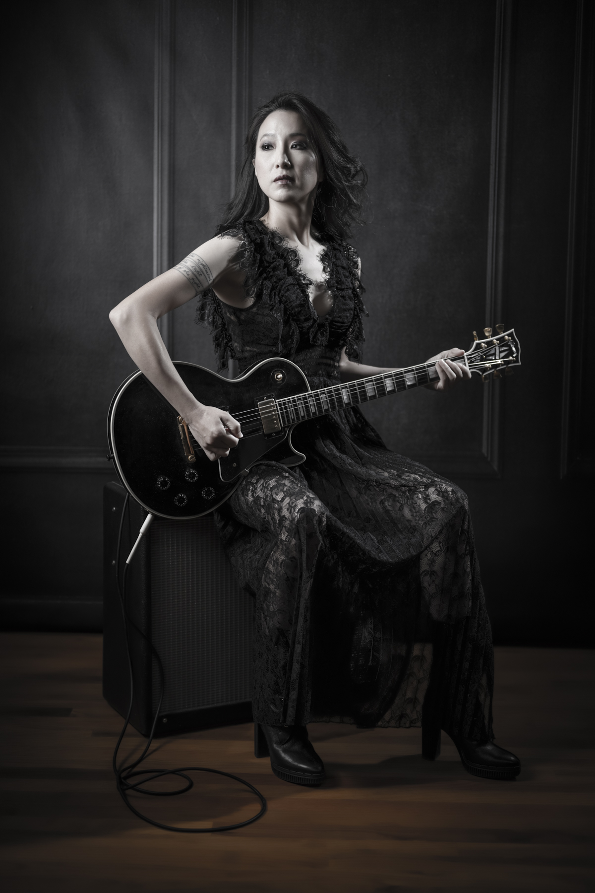 Portrait of a woman in black lace with an electric guitar