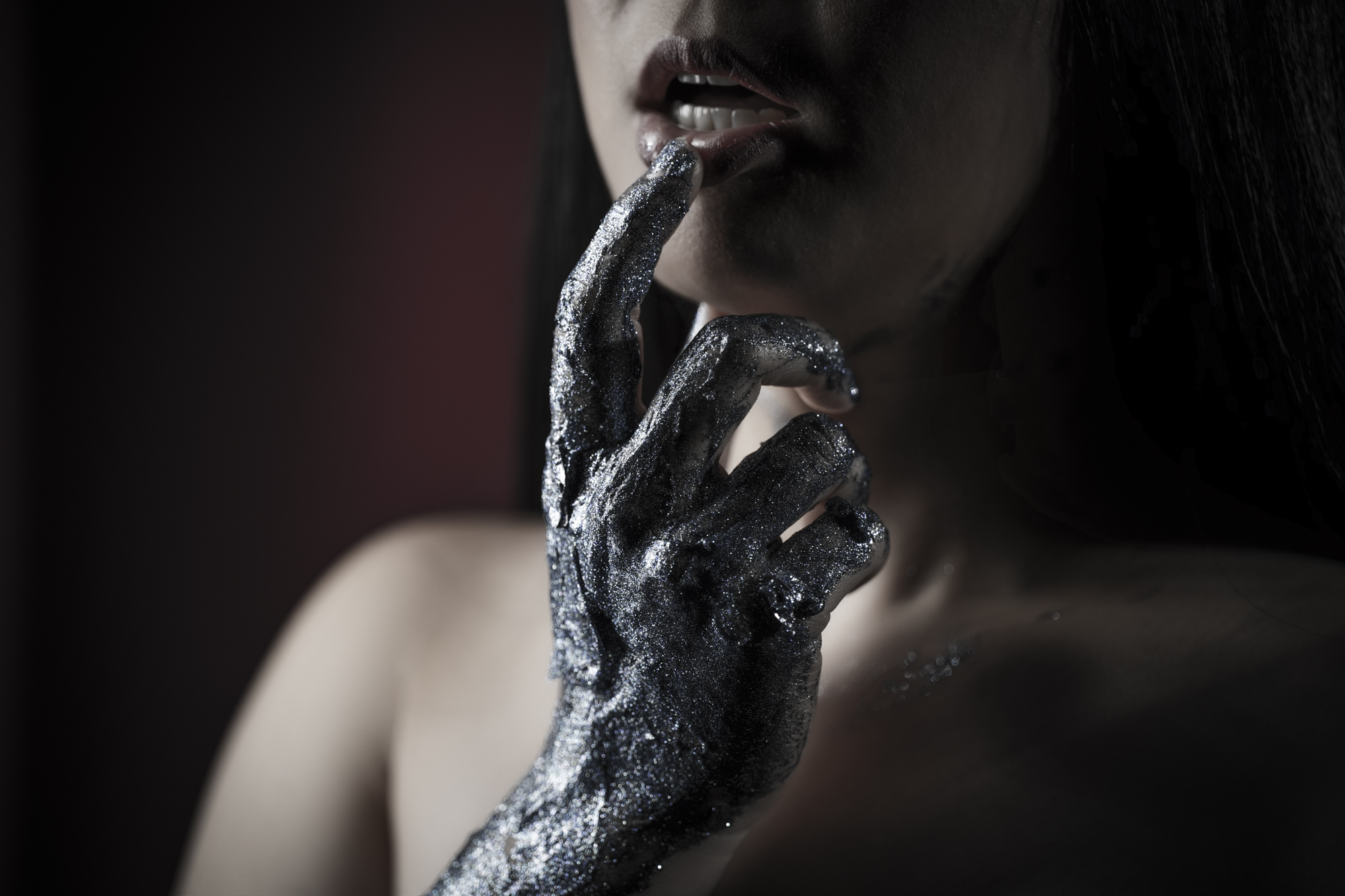 Close portrait of glitter-covered hand at the lips