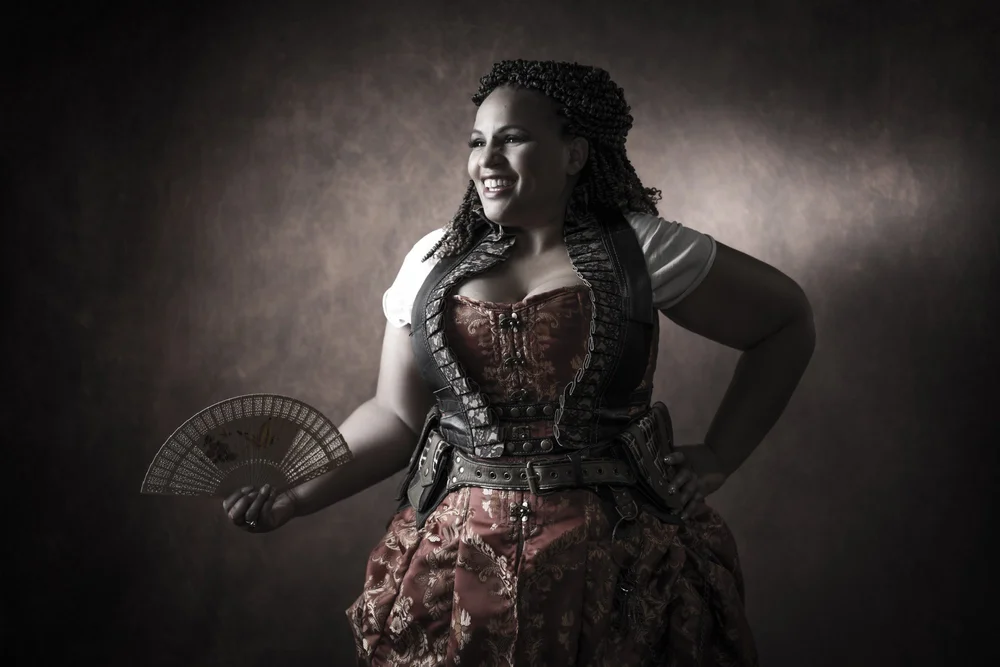 A model in a black lace robe posing under softbox light during a guided boudoir photo shoot