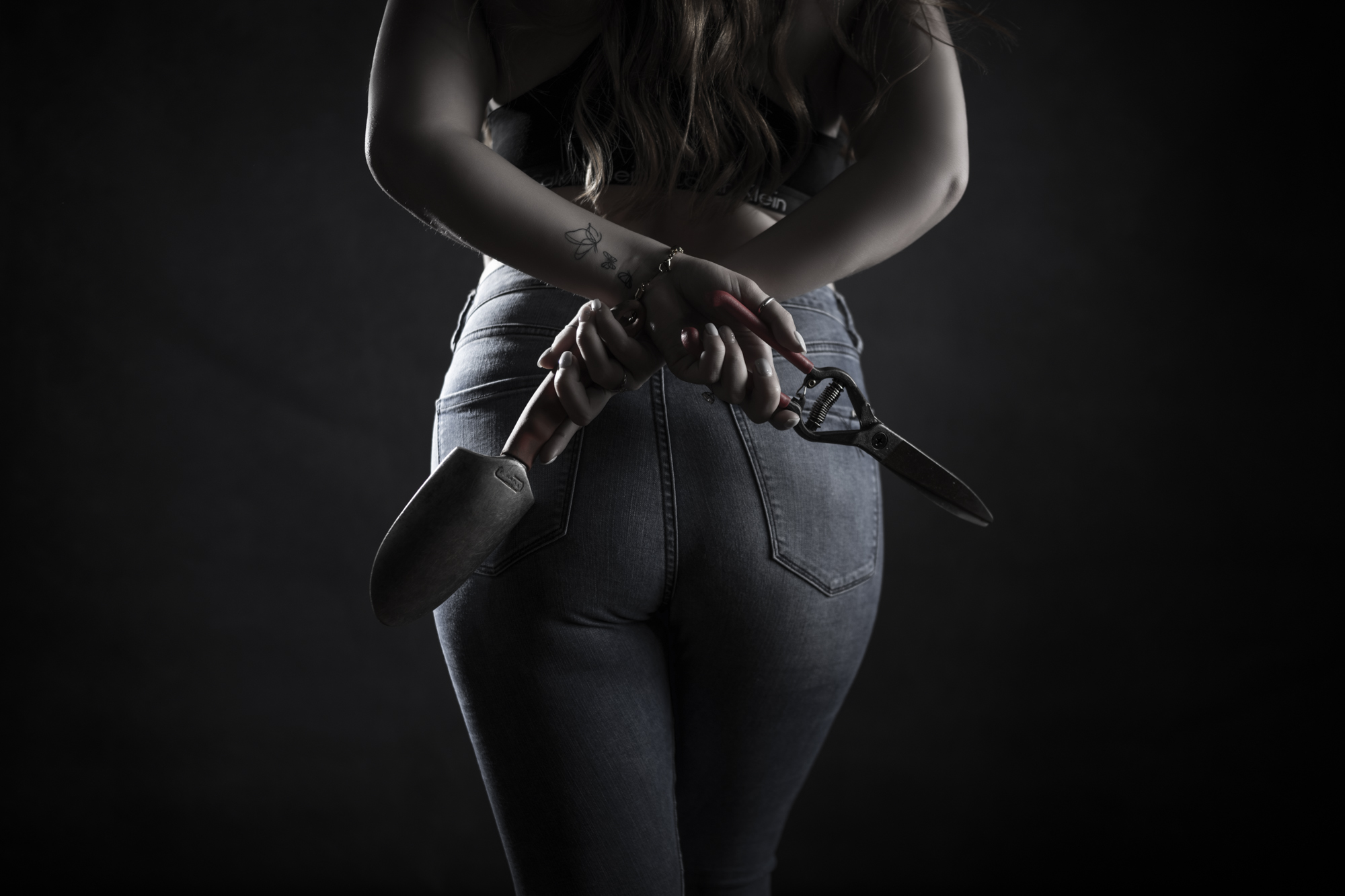 Portrait of a woman in denim holding garden tools